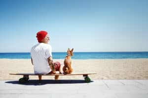 Buddy and Bello Newsletter Anmeldung Hund mit Mann auf Skateboard am Strand